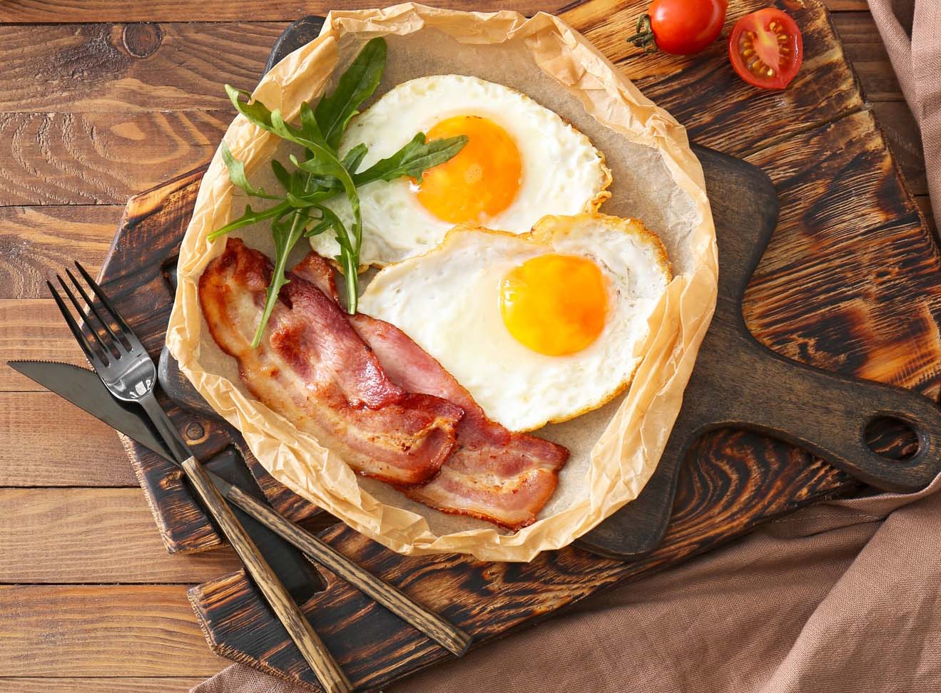 Tasty fried eggs and bacon on wooden table